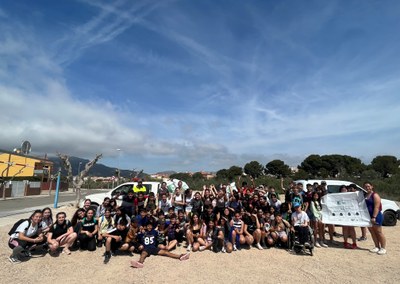 Els i les participants amb els residus recollits i el cartell amb el resultat de la recollida